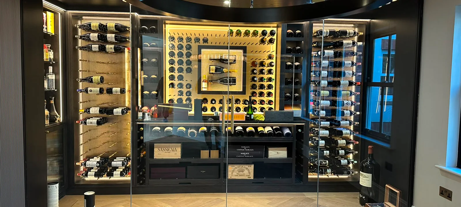 Detail of illuminated bespoke wine storage behind glazed doors
